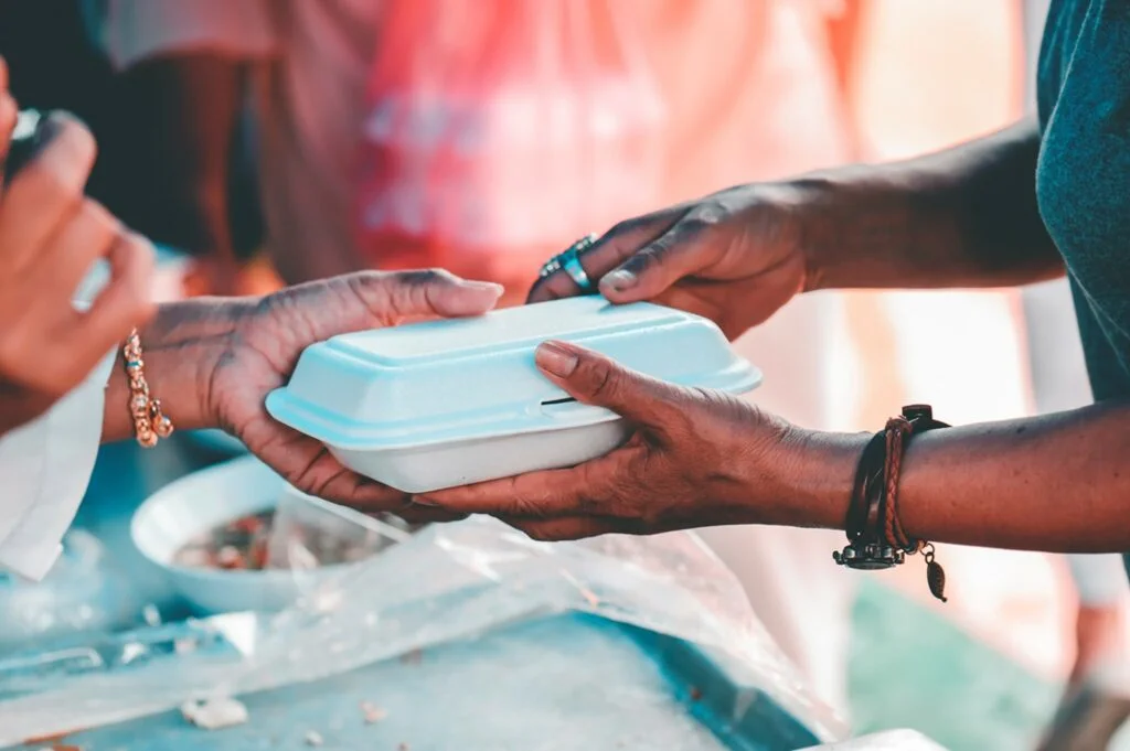 Close-up shot of two people’s hands holding prepacked foods for lunch