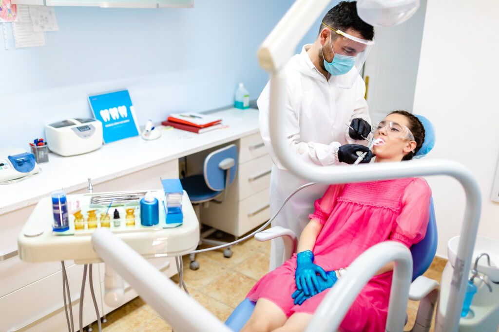 Male periodontist checking the teeth of his patient