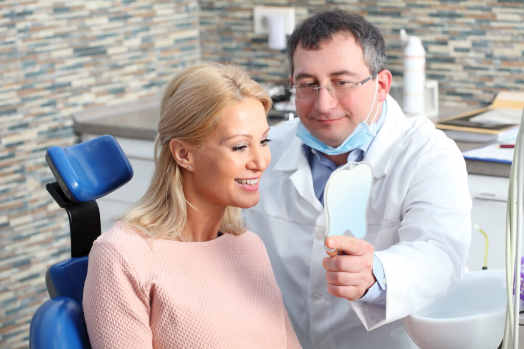 Periodontist with smiling patient while facing the mirror